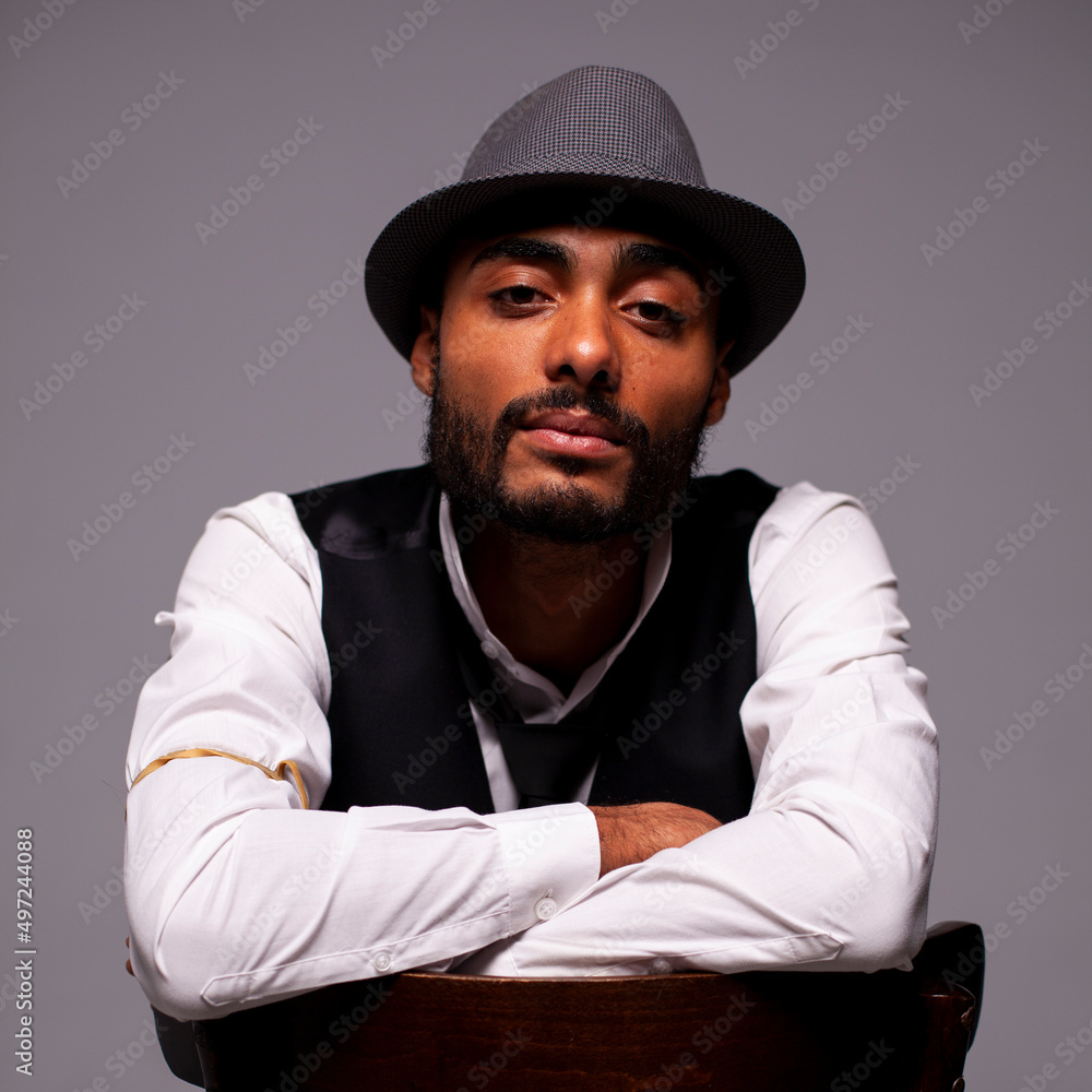 Retrato de estudio de hombre con sombrero y chaleco sobre fondo gris