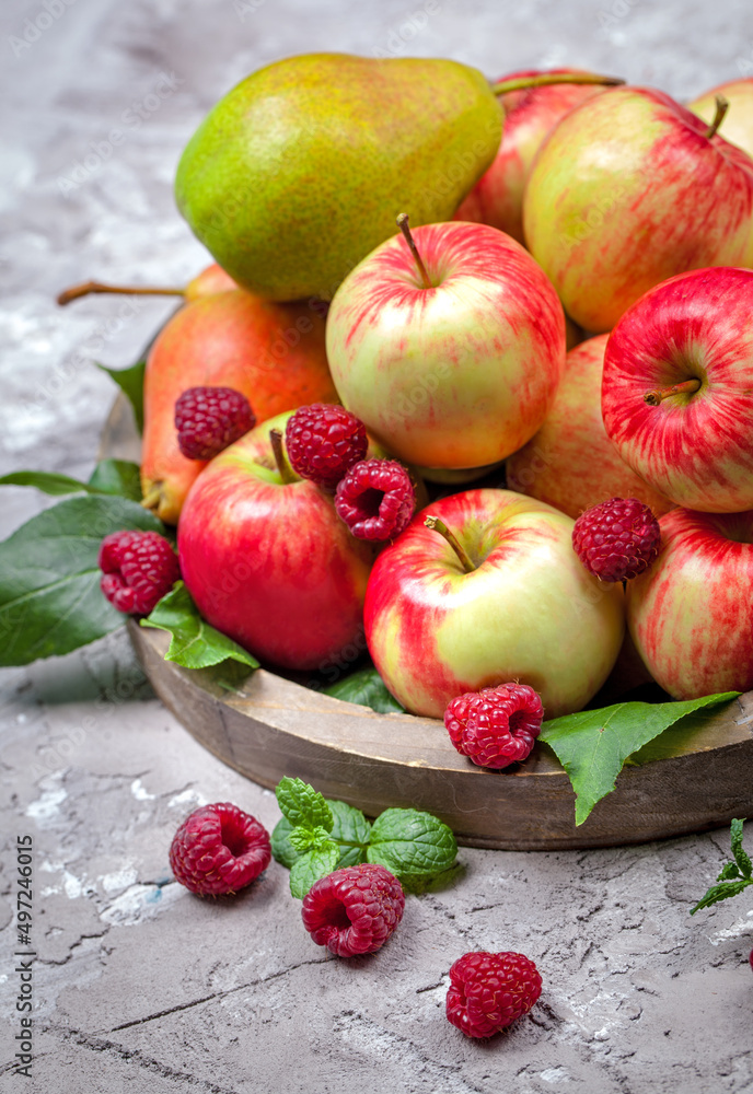 Fresh raspberries and apples on old wooden plate on a concrete background. Healthy concept. Natural healthy food. Organic food. Fresh raspberries and apples on old wooden plate on a concrete background. Healthy concept. Natural healthy food. Organic food.