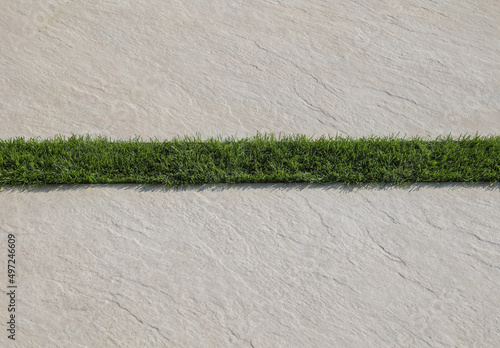 strip of green synthetic grass  between two stone tiles photo