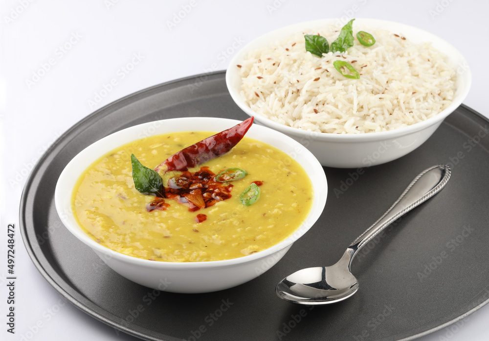 Indian popular food Dal fry or traditional Dal Tadka Curry or yellow lentil curry served with jeera rice in ceramic bowls on bamboo serving tray