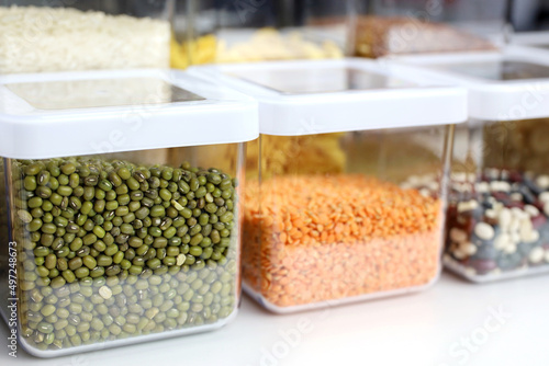 Transparent containers filled with legumes and cereals on the shelf in kitchen. Organization of storage of bulk food