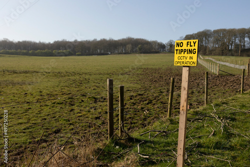 no fly tipping sign in bright yellow on the entrance to rural paddocks