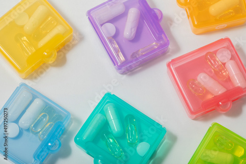 close up of a selection of multi couloured see through plastic tablet containers from above on white background photo