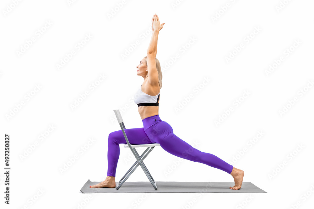 Iyengar yoga. Fit caucasian woman in purple leggings practice warrior pose  using a chair, isolated on white. Stock Photo