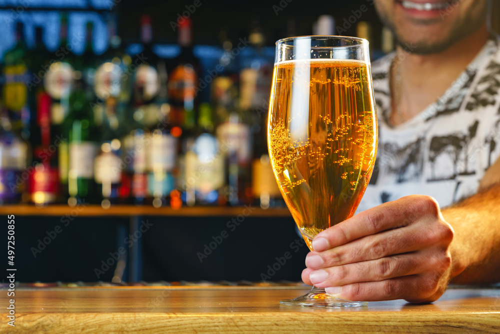 Barman serves glass of cold beer at bar counter in pub