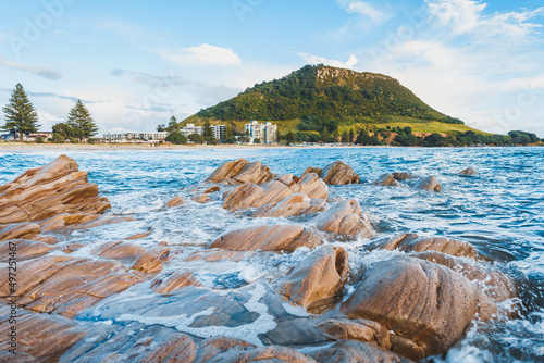 Beautiful view of rocky seashore with mount Maunganui in the background in New Zealand photo