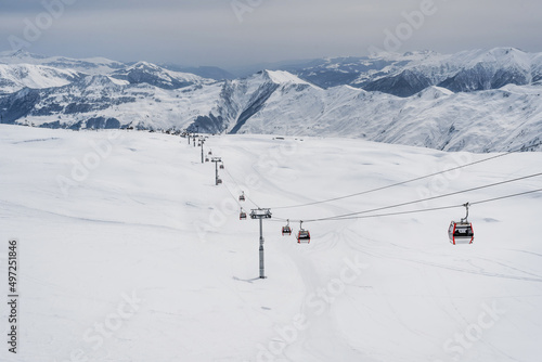 Snowy slopes with gondola to Kobi and ski tracks in nice sunny day. Ski resort Gudauri, Georgia. Caucasus Mountains. Aerial view.