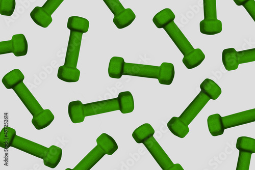 Green dumbbells in a chaotic pattern on a gray background, sports background © Liiiz