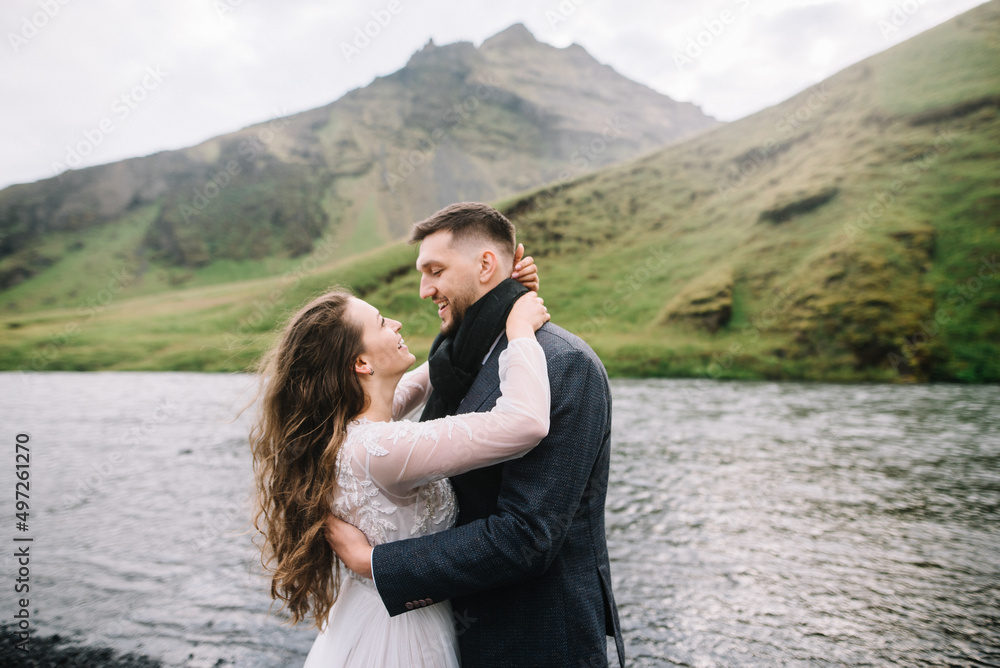 Bride and groom are looking on each other, while standing on the black volcanic stones in Icelan. Elopement at Skogafoss
