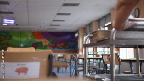 Unrecognizable cook pushing the food cart and preparing the school canteen to feed the students