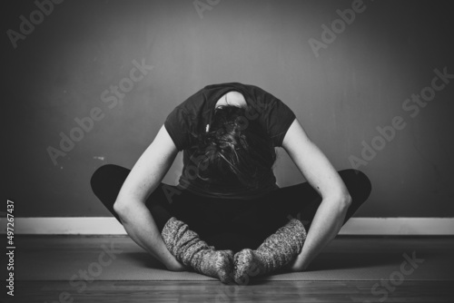 Grayscale shot of a young female practicing yin yoga in a studio photo