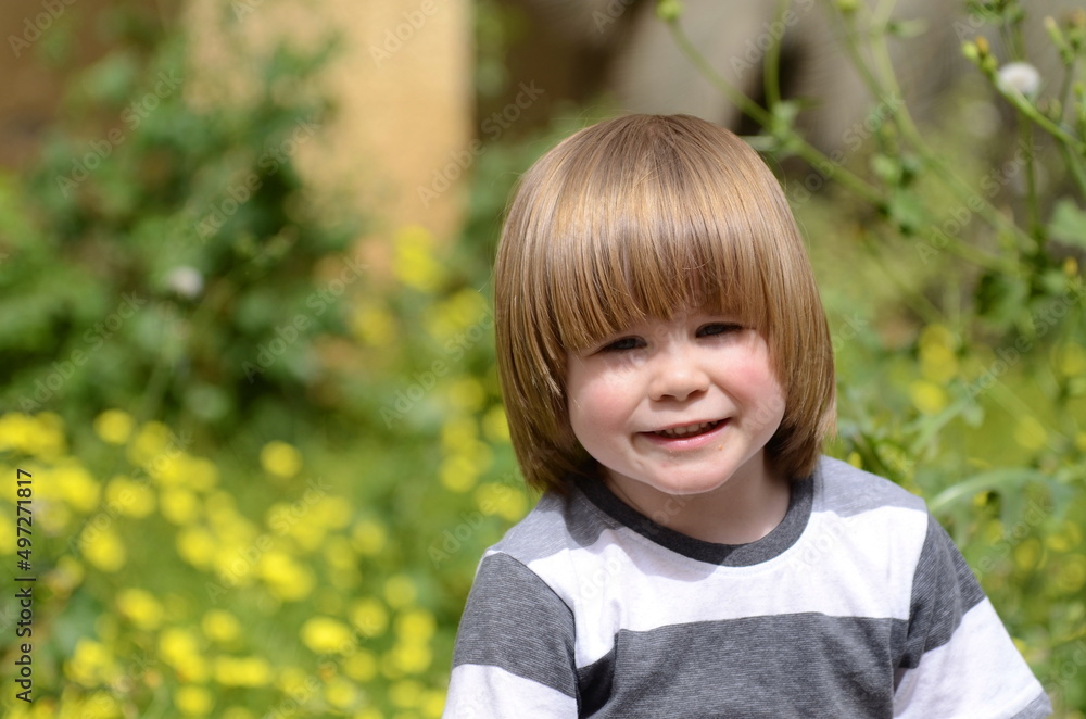 Positive kid, three years old. Portrait of a boy on a background of yellow flowers. Close-up. Positive kid, three years old. Portrait of a boy on a background of yellow flowers. Close-up.