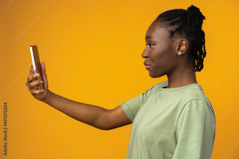 Young black woman using smartphone against yellow studio background Young black woman using smartphone against yellow studio background