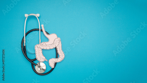 A stethoscope and large intestine shape made from paper over a blue background