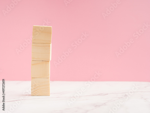 Fototapeta Naklejka Na Ścianę i Meble -  Close-up of four blank wooden cubes over a marble floor against a light pink background