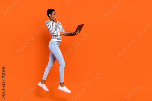 Photo of charming pretty third gender person wear pullover jumping writing device empty space isolated orange color background