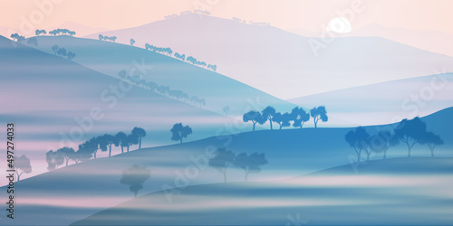 Hills and mountains covered with sparse forest. Dawn, the light of sunrise. Fog, morning haze.