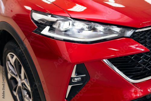 Car headlight of red automobile closeup.
