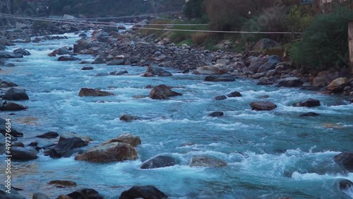 Slow motion shot of the Paravti River flowing in between mountains at Manikaran near Kasol in Himachal Pradesh, India. View of the Parvati river during the winter. Natural river in the mountains.	 photo