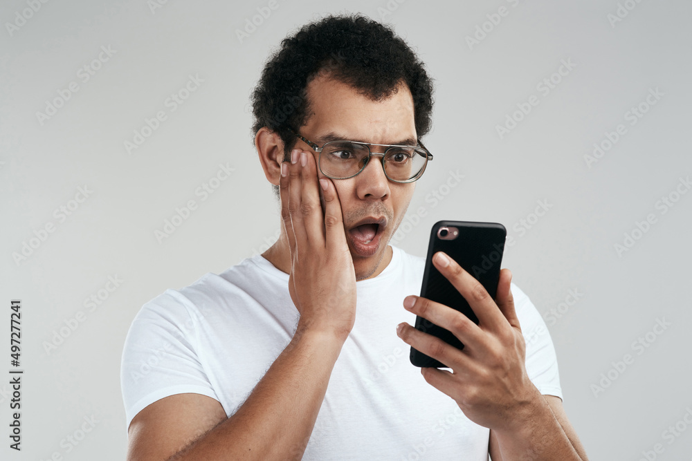 Did I just get blocked. Shot of a handsome young man using his cellphone while standing against a grey background. Did I just get blocked. Shot of a handsome young man using his cellphone while standing against a grey background.
