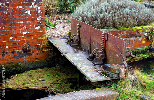 Old vintage rusty sluice gates across brick built stream in rural setting. photo