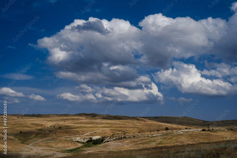 Plain and steppe with dry grass under a blue sky against background of mountains in Crimea Plain and steppe with dry grass under a blue sky against background of mountains in Crimea