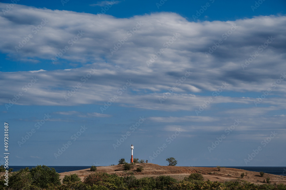 white and red lighthouse on a mountaintop above Black Sea in Crimea on summer day with a blue sky
