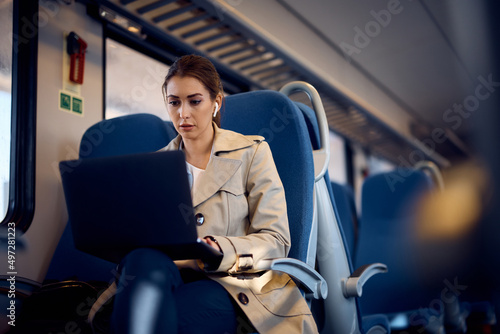 Young businesswoman works on laptop while commuting to work by train. photo