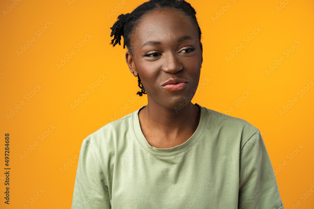Beautiful african woman having skeptical and dissatisfied look against yellow background