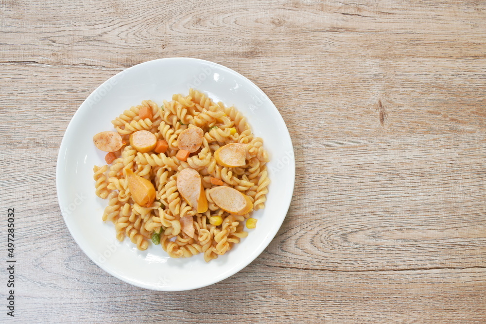 stir fried Gemelli Italian pasta with slice pork sausage and garden pea with corn in ketchup on plate stir fried Gemelli Italian pasta with slice pork sausage and garden pea with corn in ketchup on plate