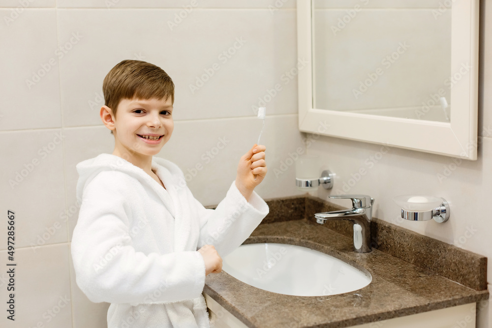A child is brushing his teeth in the bathroom. A child in a white coat is brushing his teeth. Healthy lifestyle. Healthy teeth. A child is brushing his teeth in the bathroom. A child in a white coat is brushing his teeth. Healthy lifestyle. Healthy teeth.