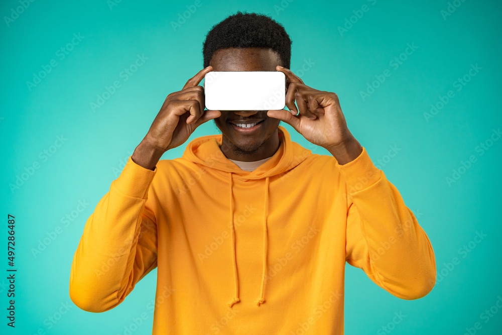 Young black man cover his face using phone in studio