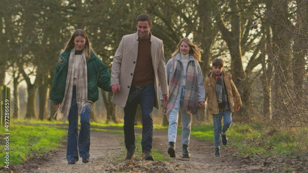 Full length shot of family holding hands on walk through autumn countryside together - shot in slow motion Full length shot of family holding hands on walk through autumn countryside together - shot in slow motion
