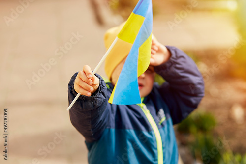 Patriotic little boy holds Ukrainian flag. Stand with Ukraine. Support Ukraine. Stop russian aggression concept. Stop war in Ukraine. Pray for Ukraine.