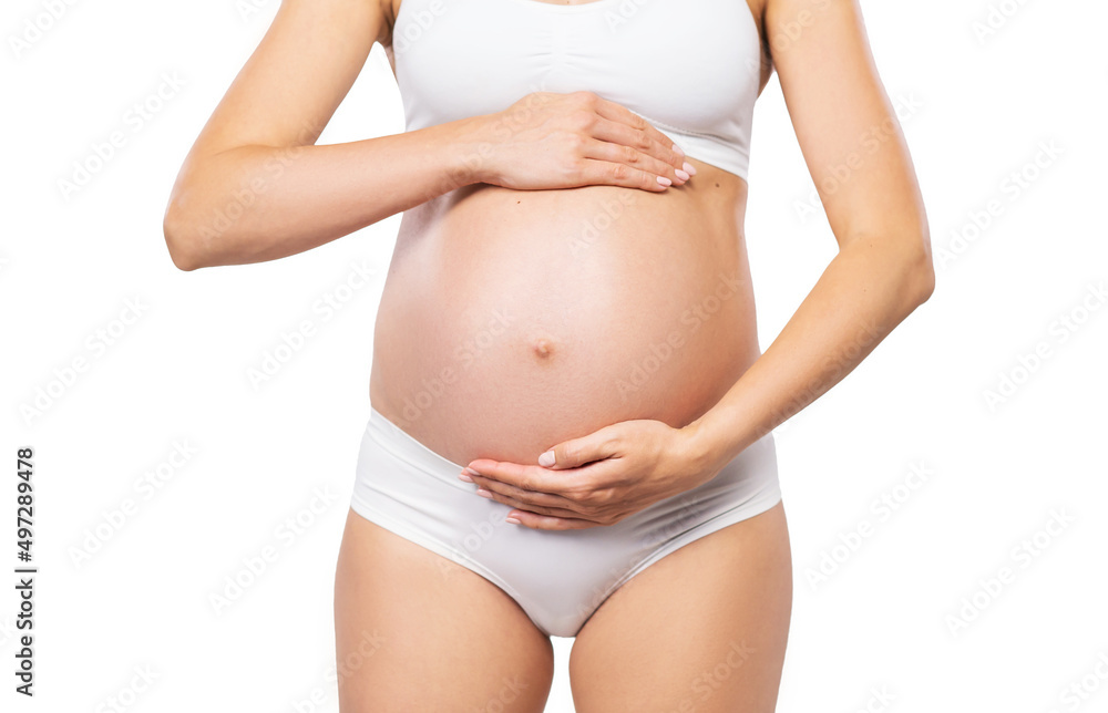 Young pregnant woman in swimsuit. Girl expecting a baby and touching her belly isolated on white background. Close-up image. Young pregnant woman in swimsuit. Girl expecting a baby and touching her belly isolated on white background. Close-up image.