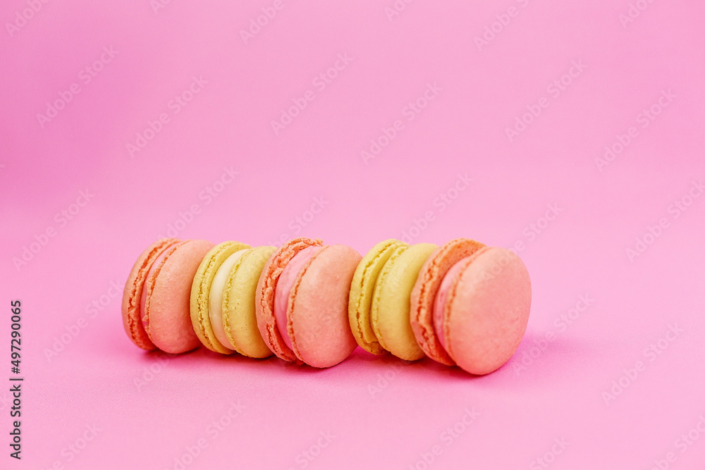 Obraz premium Close-up of a yellow almond cookie or macarons of pastel colors on a pink background with a place for writing and cutting. Minimalism.
