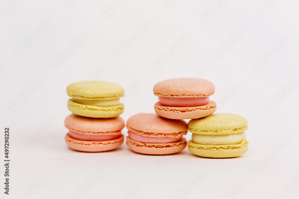 A tower of multicolored macaroons on a plain white background with a place for writing and cutting. Minimalism. Yellow, orange, pink. Beautiful cakes. Aesthetics. A tower of multicolored macaroons on a plain white background with a place for writing and cutting. Minimalism. Yellow, orange, pink. Beautiful cakes. Aesthetics.