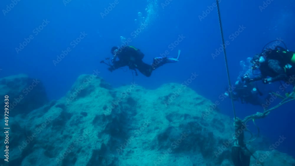 Divers swimming under the sea, between the rocks. Divers swimming under the sea, between the rocks.