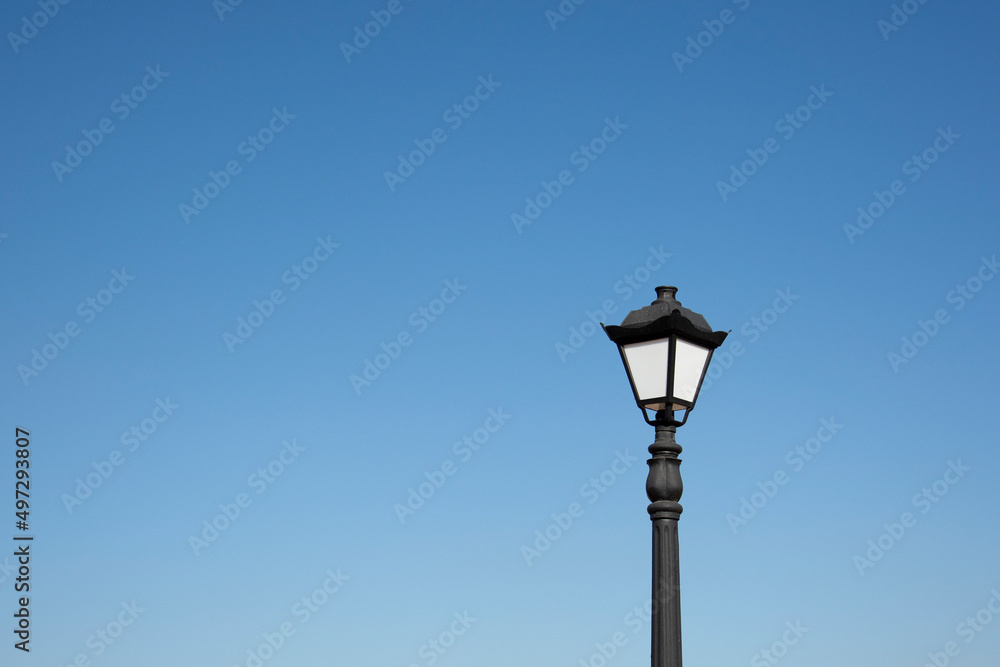 An antique lantern on a blue sky background. Vintage street lamp in the daytime.

