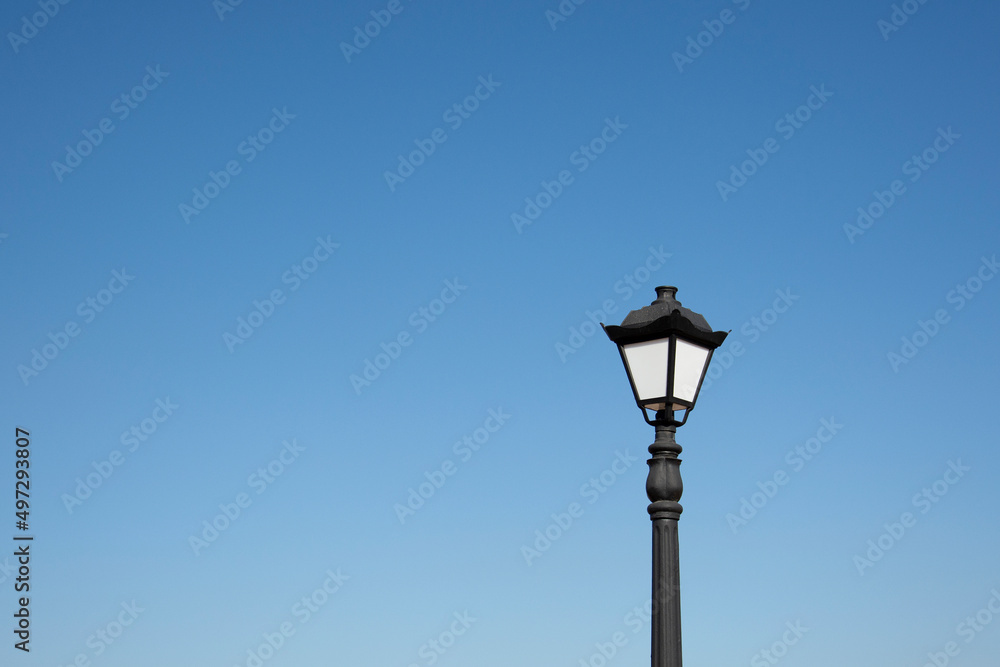 An antique lantern on a blue sky background. Vintage street lamp in the daytime.
An antique lantern on a blue sky background. Vintage street lamp in the daytime.