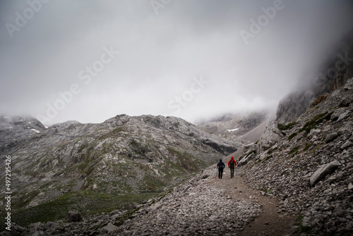 Two hikers walk along the trail into the dark fog