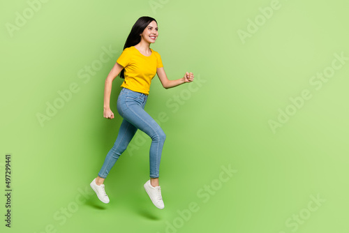 Full length profile portrait of cheerful pretty lady hurry look empty space isolated on green color background