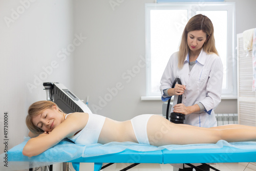 Full length shot of vibration massage procedure in the cosmetologist office. Massage is useful for the effect of orange peel on the thighs  fights well with fat deposits  triggers metabolic processes