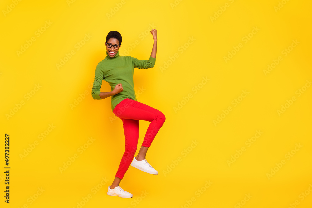 Photo of funky cute short hair lady dressed green turtleneck walking rising fists empty space isolated yellow color background