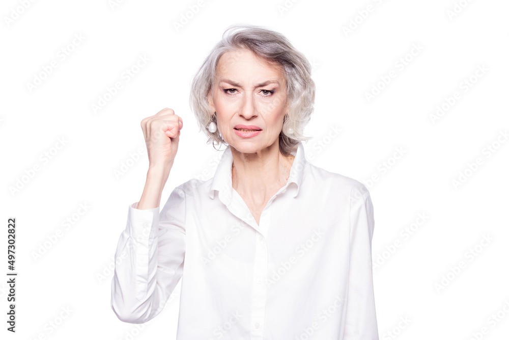 Portrait of an angry attractive mature woman frowning at the camera and shaking her fist in the air with a menacing look isolated on white background Portrait of an angry attractive mature woman frowning at the camera and shaking her fist in the air with a menacing look isolated on white background