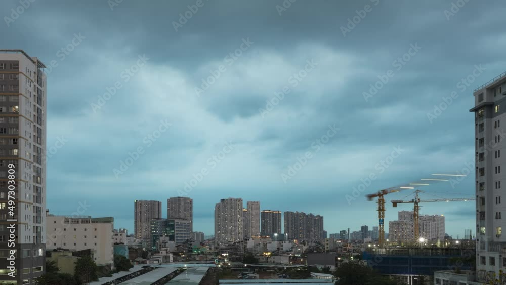 day to night time lapse of residential high rise buildings with working cranes on an adjacent construction site day to night time lapse of residential high rise buildings with working cranes on an adjacent construction site
