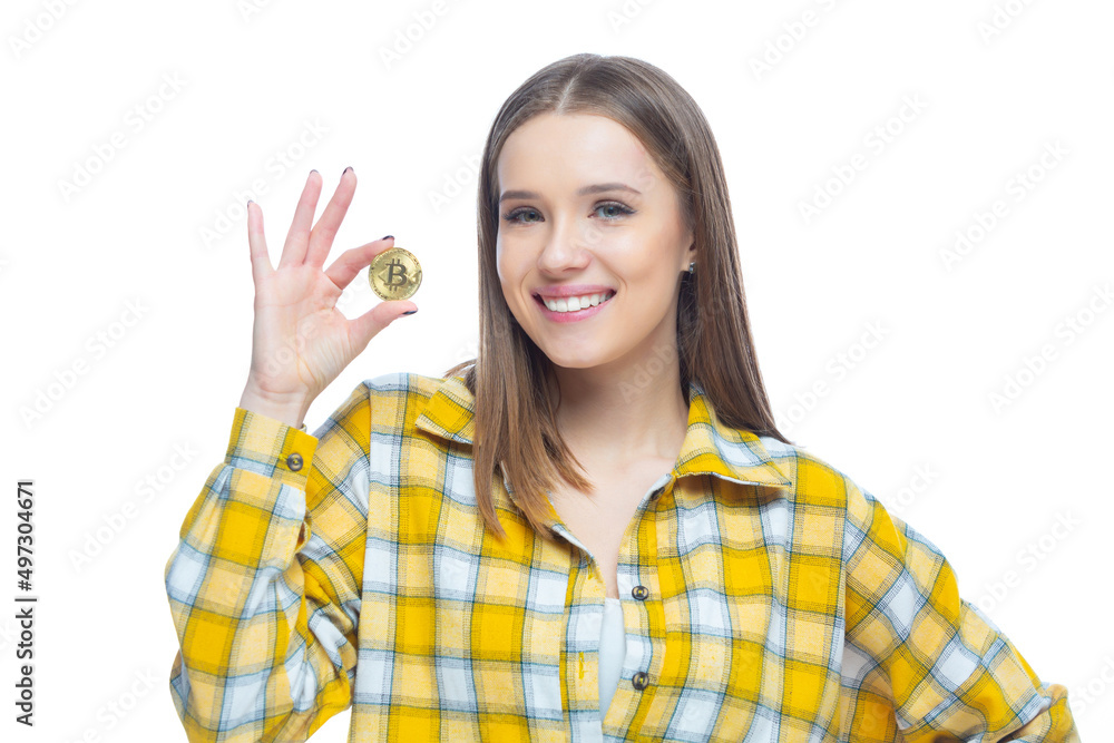Closeup of cute smiling girl holding a physical bitcoin cryptocurrency in her hand isolated on white background. Concept of financial literacy, innovation, success Closeup of cute smiling girl holding a physical bitcoin cryptocurrency in her hand isolated on white background. Concept of financial literacy, innovation, success