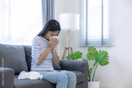 Young Asian woman sick with a cold, She sneezed and had a runny nose.