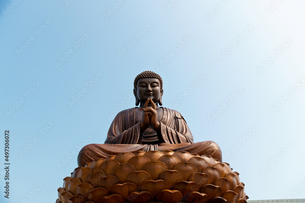 Fototapeta premium Wooden Buddha statue under blue sky