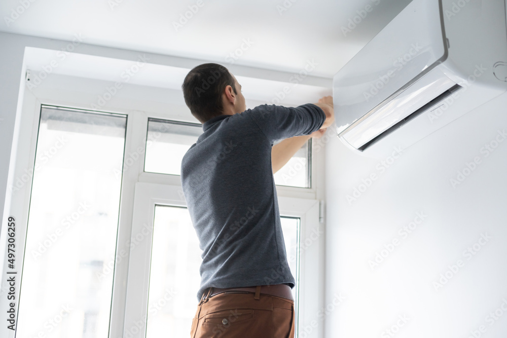 Professional technician maintaining modern air conditioner indoors Professional technician maintaining modern air conditioner indoors
